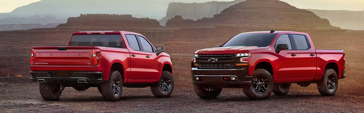 Photo of two Chevrolet Silverado 1500 vehicles parked side by side on a sand terrain